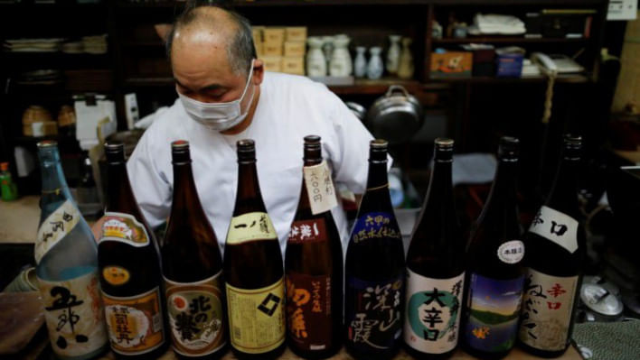 রেস্তোরাঁ বন্ধের আগে মদের বোতল সাজাচ্ছেন জাপানের এক রেস্তোরাঁ মালিক। ফাইল ছবি: রয়টার্স