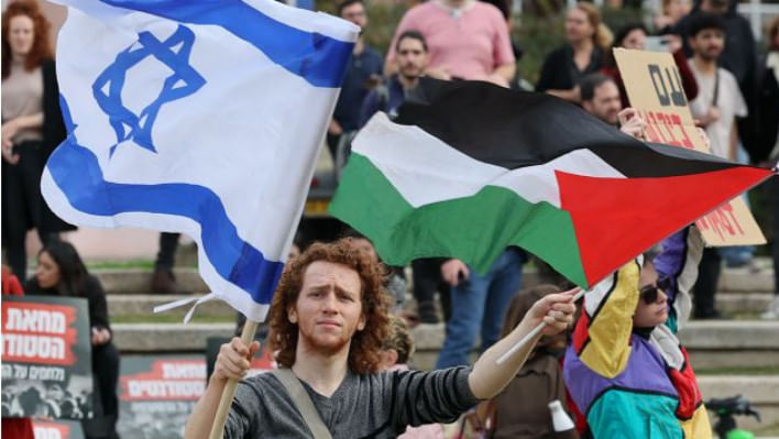 ফিলিস্তিন ও ইসরায়েলের পতাকা উড়িয়ে নব-নির্বাচিত নেতানিয়াহু সরকারের বিরুদ্ধে বিক্ষোভ প্রকাশ করছেন তেল আভিভ বিশ্ববিদ্যালয়ের এক ইসরায়েলি শিক্ষার্থী। ফাইল ছবি: এএফপি (২০২৩)