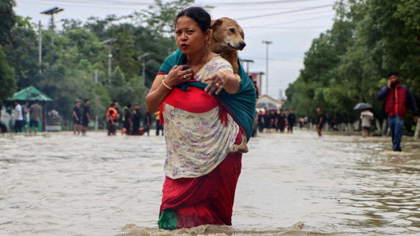 ভারতের মণিপুর রাজ্যের রাজধানী ইমফালে এক নারী বন্যার হাত থেকে নিজেকে ও তার পোষা কুকুরকে রক্ষার চেষ্টা চালাচ্ছেন। ছবি: এএফপি (১ জুন, ২০২৫)