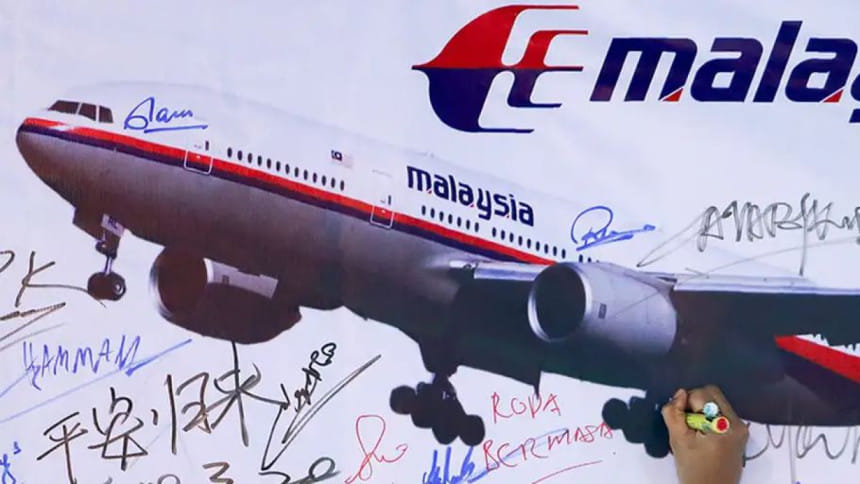 হারিয়ে যাওয়া এমএইচ ৩৭০ উড়োজাহাজের ছবি সম্বলিত একটি বোর্ডে সই করছেন এক নারী। ফাইল ছবি: রয়টার্স