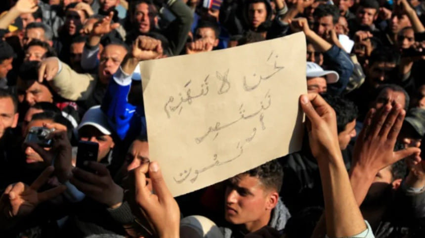 সিদি বোজিদে ক্ষমতাসীন দলের বিরুদ্ধে বিক্ষোভ করছে তিউনিসিয়ার জনগণ। প্ল্যাকার্ডে লেখা, ‘আমরা পরাজিত হব না। বিজয় অথবা মৃত্যু’। ফাইল ছবি” জোহরা বেনসেমরা/রয়টার্স (জানুয়ারি ২০১১) 