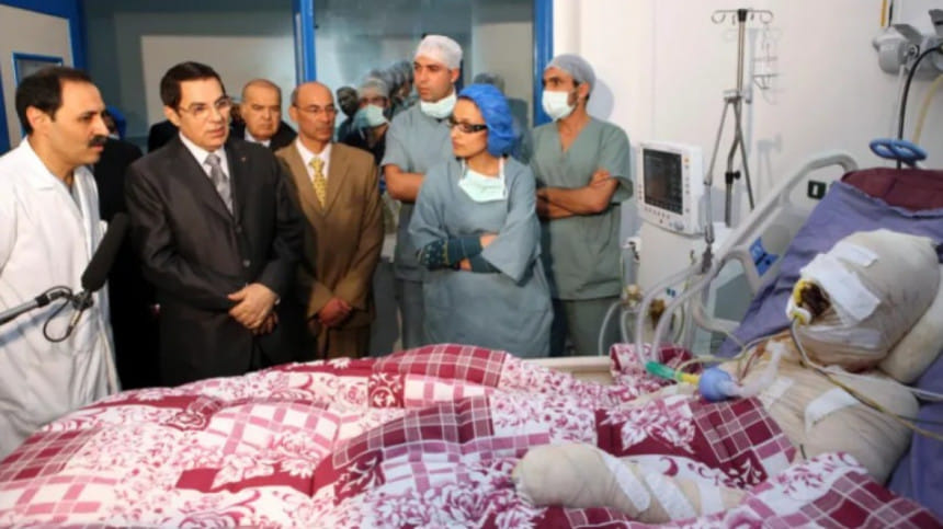 তিউনিসিয়ার সাবেক স্বৈরশাসক জয়নাল আবেদিন বেন আলি হাসপাতালে মোহাম্মদ বোয়াজিজিকে দেখতে যান। সরকারি কর্মকর্তাদের লাঞ্ছনার যন্ত্রণা সহ্য করতে না পেরে নিজের গায়ে আগুন দেন বোয়াজিজি। ফাইল ছবি: রয়টার্স (২৮ ডিসেম্বর, ২০১০) 