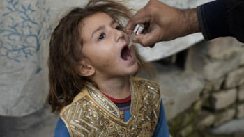 পাকিস্তানের এক শিশুকে পোলিওর ভ্যাকসিন খাওয়াচ্ছেন একজন স্বাস্থ্যকর্মী। ছবি: এপি