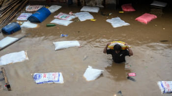 কাঠামান্ডুতে বুক সমান বন্যার পানিতে এক বস্তা ময়দা ও নিজেকে বাঁচানোর চেষ্টা করছেন এক নেপালি। ছবি: এএফপি