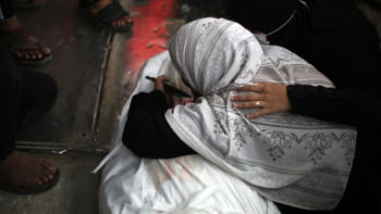 নিহত ফিলিস্তিনির মরদেহের সামনে শোক প্রকাশ করছেন এক নারী। ছবি: এএফপি